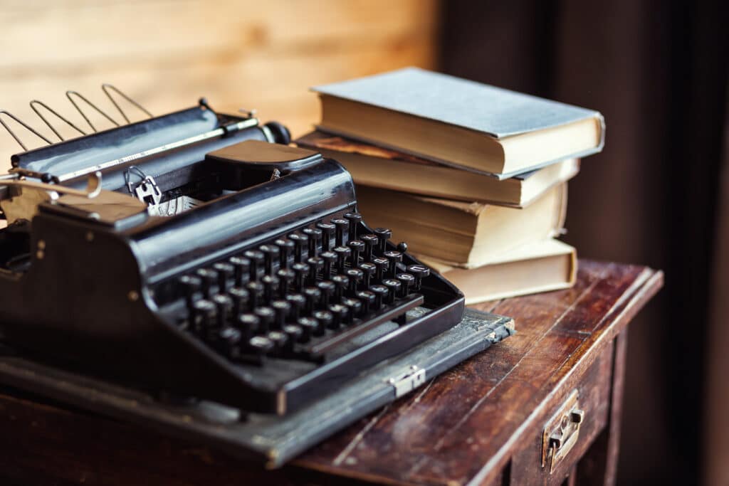 Alte Schreibmaschine und Bücher auf einem Holztisch