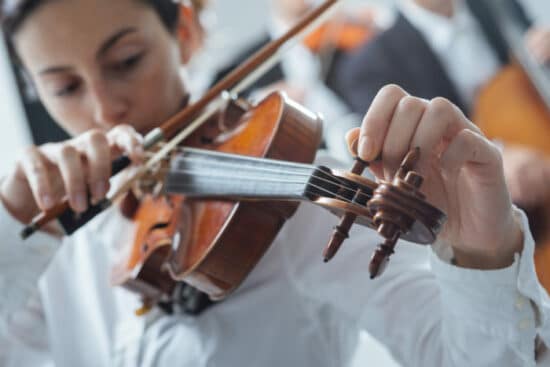 Frau stimmt Geige, um richtige Tonalität zu treffen