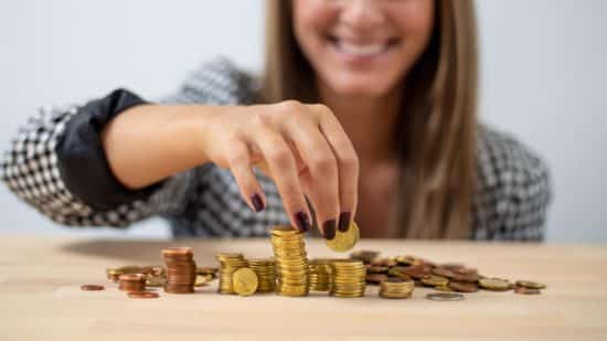 Finanzdienstleister auf Social Media – Frau stapelt Geldmünzen auf Tisch