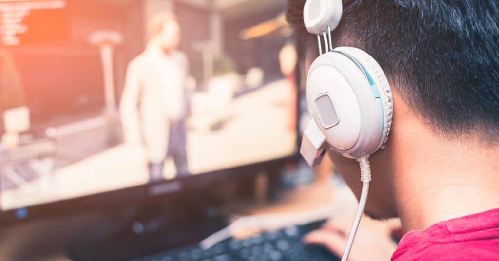 Männlicher Gamer mit Kopfhörern am PC