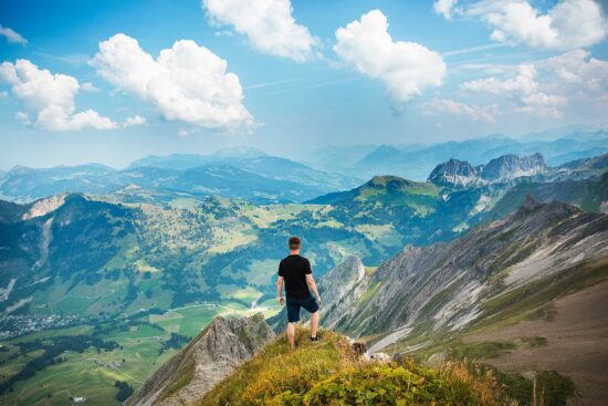 Mann steht auf Hügel und blickt über idyllische Landschaft